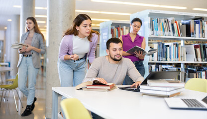 Young guy and girl students studying in the university library are preparing an abstract on a...