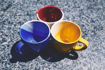 Tea time. Coffee break. Blue yellow red cups on marble