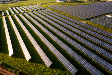 Drone view of solar panels on agricultural field during sunny day. The landscape is fully equipment...