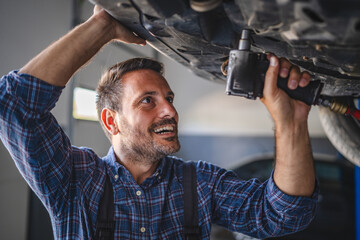 Car mechanic use a tool to repair automobile undercarriage system