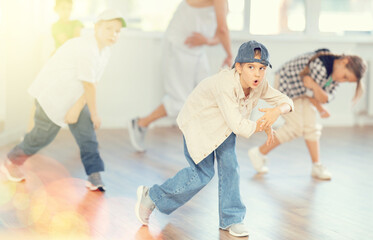 Fototapeta premium Young girl and group of positive children practicing energetic hip hop movements at modern dance school