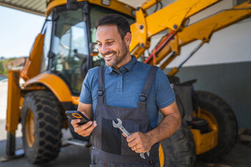 car mechanic stand with tool by machinery and use mobile phone