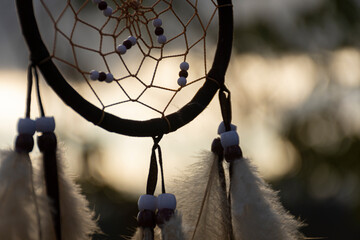 A partial image of a handmade dream catcher against a golden evening sky. 