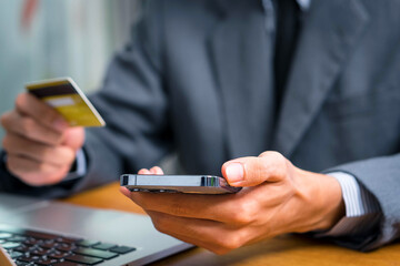 Close up Male hands holding credit card and smartphone, man paying online, credit card shopping, using banking service, entering information, shopping, ordering in internet store, doing secure payment