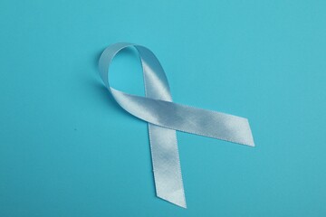 Light blue ribbon on color background, top view. Prostate cancer awareness