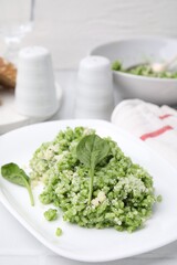 Delicious spinach risotto with parmesan cheese on white tiled table