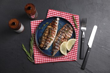 Plate with delicious grilled mackerel served on dark textured table, flat lay