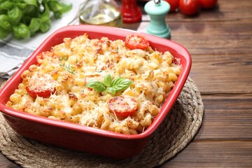 Delicious al forno pasta in baking dish on wooden table, closeup