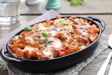 Delicious al forno pasta in baking dish on wooden table, closeup