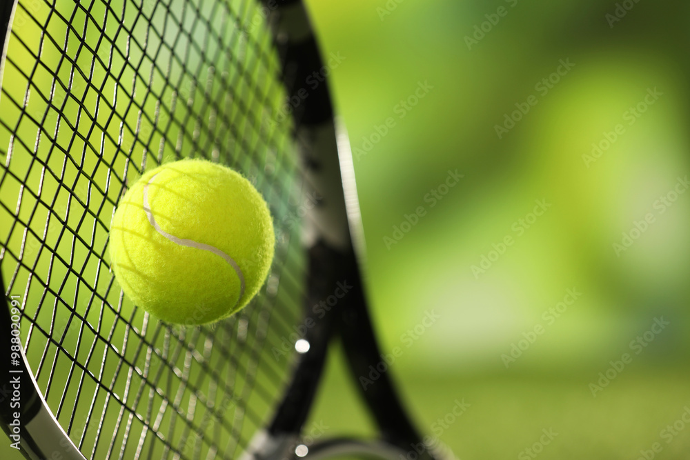 Sticker Tennis racket with ball against blurred green background, closeup. Space for text