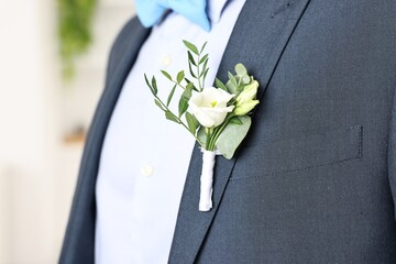 Groom in suit with stylish boutonniere indoors, closeup