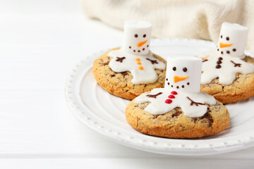 Delicious cookies with snowmen made of marshmallows on white table, closeup. Space for text