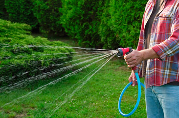 Man watering lawn with hose in backyard, closeup