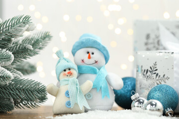Funny snowman figure and other Christmas decor on artificial snow against blurred lights