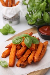 Sweet potato fries, basil and ketchup on table, closeup