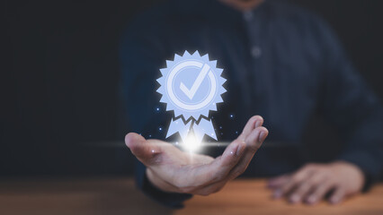A businessman holds a glowing digital certification badge with a checkmark symbol, representing quality, trust, and achievement. The futuristic design highlights success and recognition.