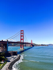 Golden Gate Bridge, a famous landmark of San Francisco, Northern California, United States, captured on a clear day stretching over the ocean and framed by a beautiful blue sky. 