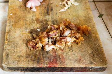 A close-up of crispy fried chicken meat pieces on a wooden cutting board. The chicken is golden brown and has a crispy texture.