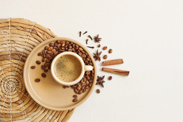 Cup of hot coffee with coffee beans and cinnamon on the plate on the light background. Top view.
