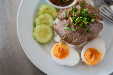 Slice of stewed pork eaten with rice served with boiled egg and cucumber sprinkled with coriander. Close up