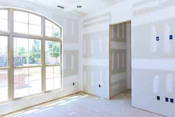 Plaster has been applied to interior walls ceiling of new house and is ready for paint priming.