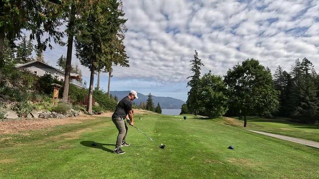 Asia man hits a golf driver in a beautiful golf course at Bowen Island Bc Canada