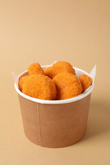 Fried mozzarella in a cardboard box on a beige background