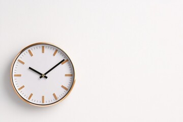 A close-up of a minimalist clock on a white wall, with no other decorations, emphasizing simplicity and function