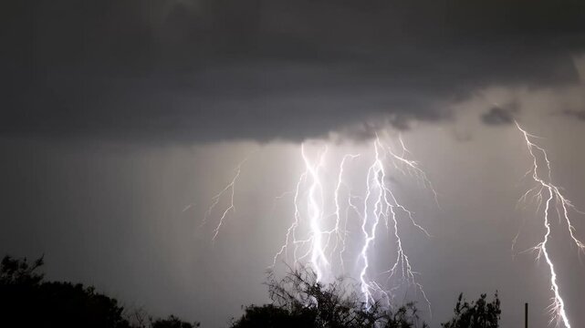 Thunderstorm flashes with multiple bolts of lightning on dark cloudy sky