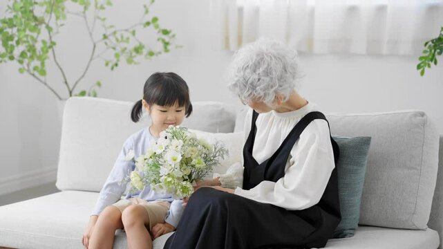 花束を持った孫と祖母　ファミリーイメージ	
