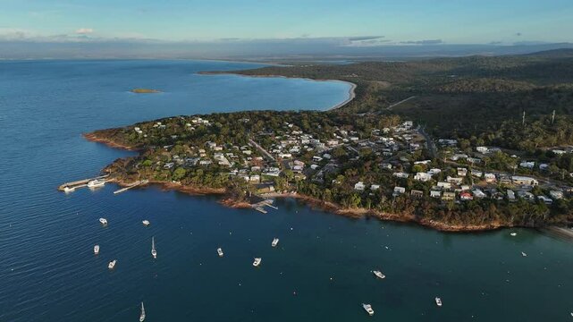 Aerial establishing shot of Coles Bay Town with parking boats at sunrise. Small city at coastline of Tasmania, Australia. Wide shot.