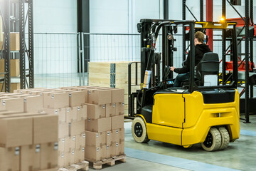 Warehouse forklift at work. Man operates machine for loading pallets. Warehouse with boxes inside industrial building. Yellow forklift. Warehouse equipment. Forklift for unloading.