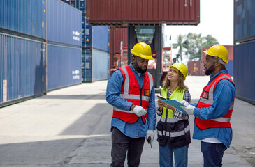 Group of shipment worker dressed in hardhat, safety vest and protective glove working during the day under sunlight. There are heavy duty container forklift in the work area.