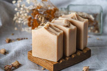 Delicate natural soap in pastel colors on a wooden soap dish on a background of gray fabric