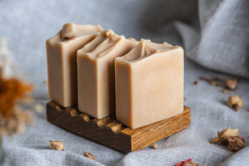 Delicate natural soap in pastel colors on a wooden soap dish on a background of gray fabric