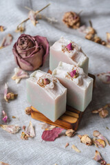 Delicate pieces of natural floral soap decorated with rosebuds in a wooden soap dish. A beautiful postcard