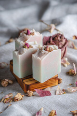 Delicate pieces of natural floral soap decorated with rosebuds in a wooden soap dish. A beautiful postcard