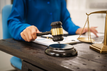 An Asian female lawyer sits at her desk in the office,working on legal documents with computer,providing online legal consulting,reviewing contracts,drafting wills,offering signature certification