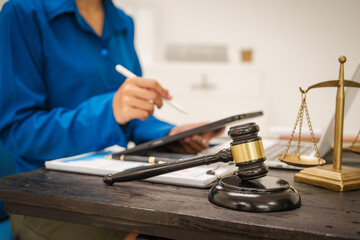 An Asian female lawyer sits at her desk in the office,working on legal documents with computer,providing online legal consulting,reviewing contracts,drafting wills,offering signature certification