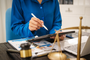 An Asian female lawyer sits at her desk in the office,working on legal documents with computer,providing online legal consulting,reviewing contracts,drafting wills,offering signature certification