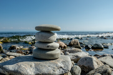 Fototapeta premium Handmade soap pieces in the shape of stones are stacked on top of each other on the shore of the sea or lake. Image of organic cosmetics in a natural environment