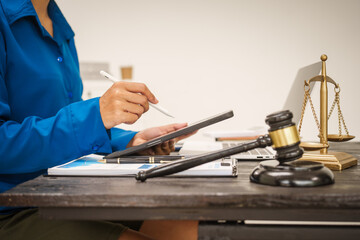 An Asian female lawyer sits at her desk in the office,working on legal documents with computer,providing online legal consulting,reviewing contracts,drafting wills,offering signature certification