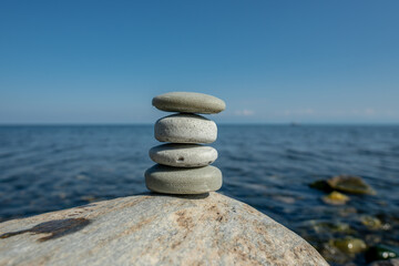 Pieces of craft soap in the shape of stones are stacked on top of each other against the background of the sea or lake. Image of organic cosmetics in a natural environment