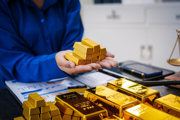 An Asian businesswoman is sitting at her desk in the office, analyzing gold bullion prices, the gold market, government policies, oil prices, inflation, and the potential to invest in digital gold.