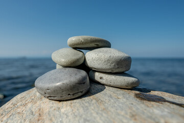 Pieces of craft soap in the shape of stones are stacked on top of each other against the background of the sea or lake. Image of organic cosmetics in a natural environment