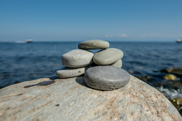 Pieces of craft soap in the shape of stones are stacked on top of each other against the background of the sea or lake. Image of organic cosmetics in a natural environment