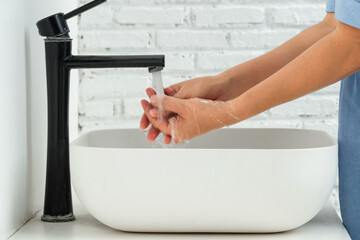 hand of beauty woman wash your hands at the wash basin with foam, cleanse the skin and have water flowing through the hands. Health and beauty concepts	