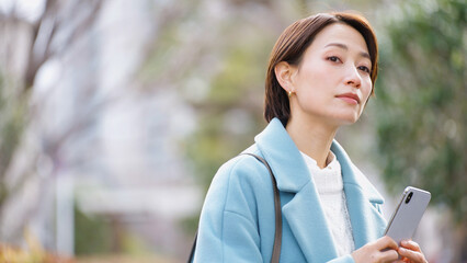 スマホを使う女性（冬服・上着・コート）