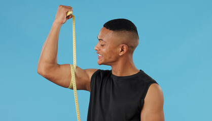 Man, arm and measuring muscle in studio, check and bodybuilder flexing on blue background. Male person, fitness and strong guy for results of weightlifting, monitor progress and tool for development