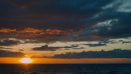 Fototapeta premium Sunset in front of the clouds the sky is over the salt water ocean